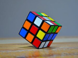 Colorful close-up view of a Rubik's Cube puzzle tilted on a wooden surface.